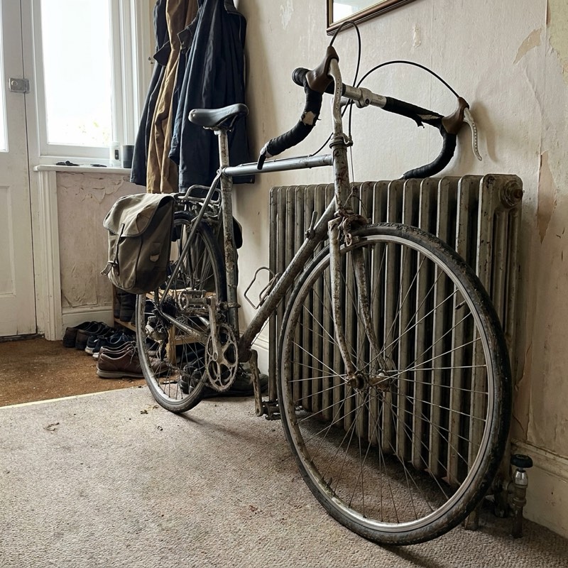 A used road bicycle leaning against a hallway radiator.