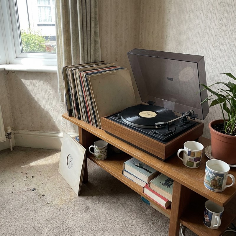 A 1970s record player beside a stack of vinyl.